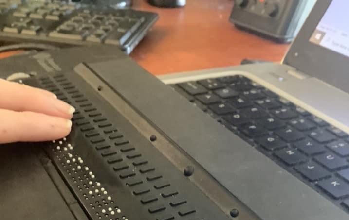 Jen reading a line of text on a 40-cell/40-characters refreshable braille display for one of her classes