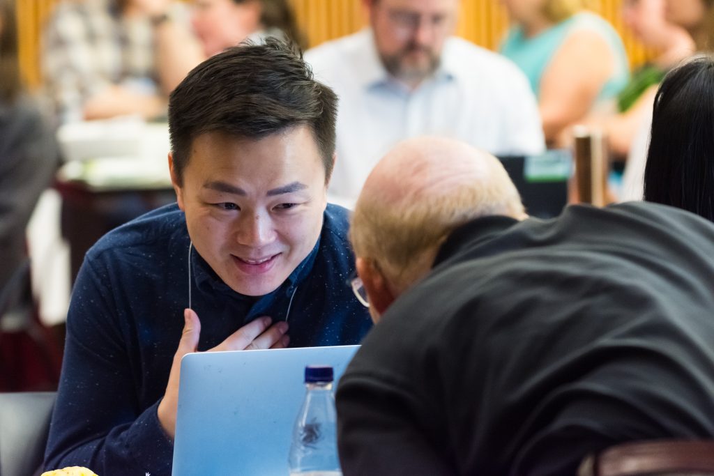 Two people talking over a laptop at a conference.