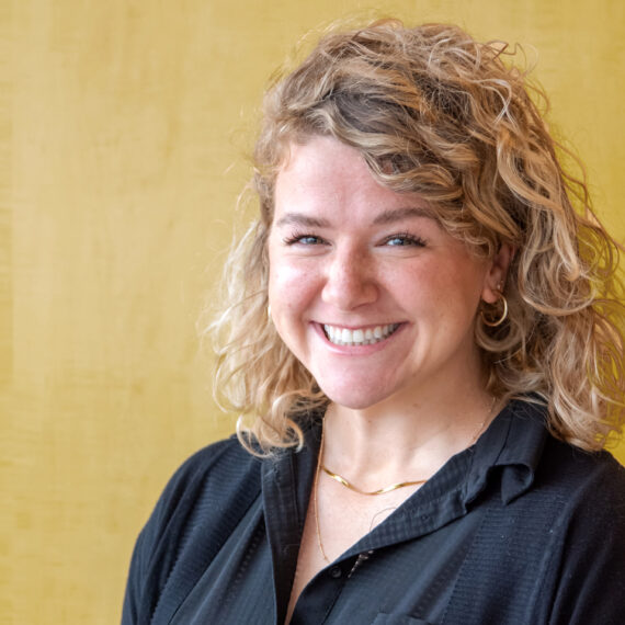 Head shot of Nina black formal shirt on a yellow background