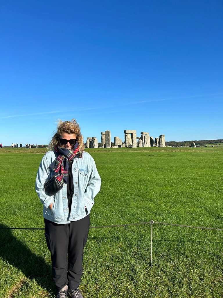 Nina picture in United Kingdom. She is standing outside on a green patch of land.