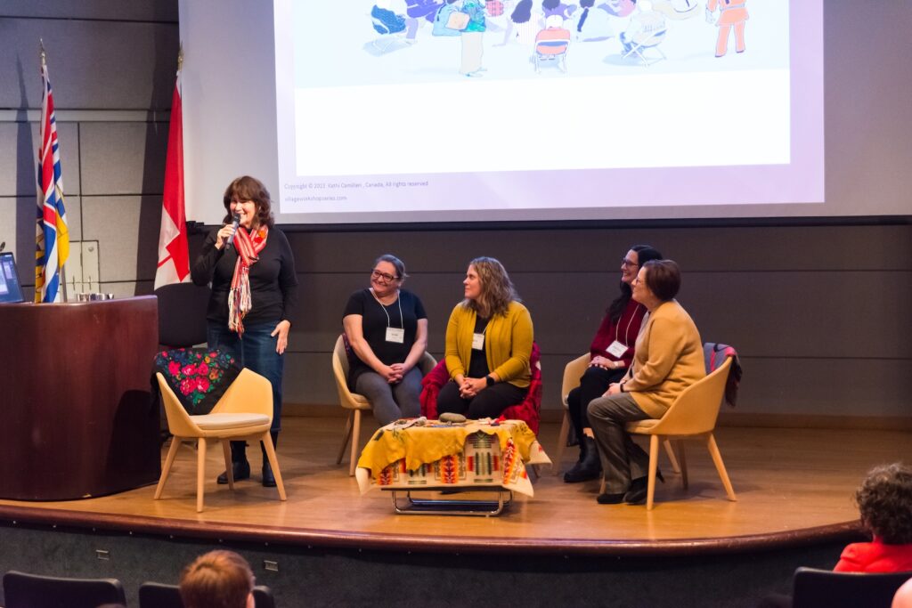 Image of the stage at Studio 23 for day 1's keynote. The presenter, Kathi Camilleri, is joined on stage with three participants.