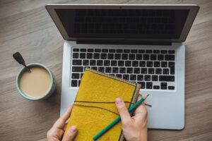 Laptop and coffee cup in girl's hands sitting on a wooden background by Boyarkinamarina