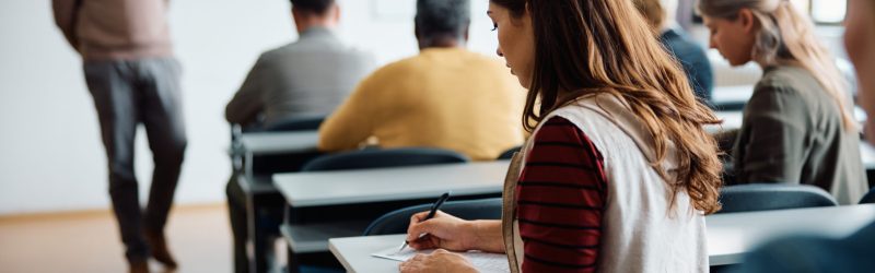 Rear view of woman writing an educational exam in the classroom.
